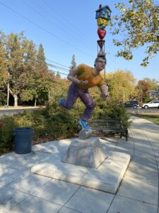 A sculpture depicting a man balancing various colorful items on his head